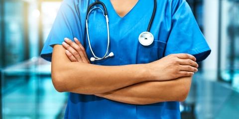 A doctor stands in a hallway with arms folded
