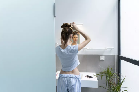 A woman looks in the mirror